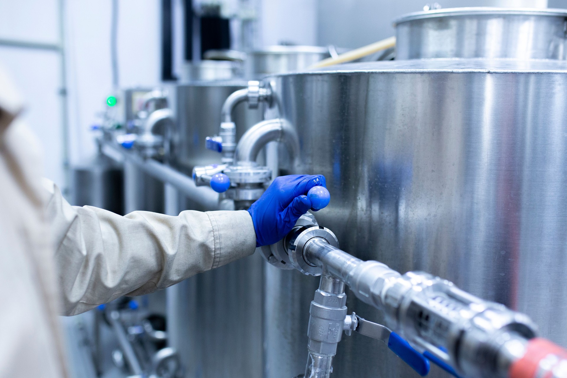a worker's hand turning the water valve of a pipeling on the factory